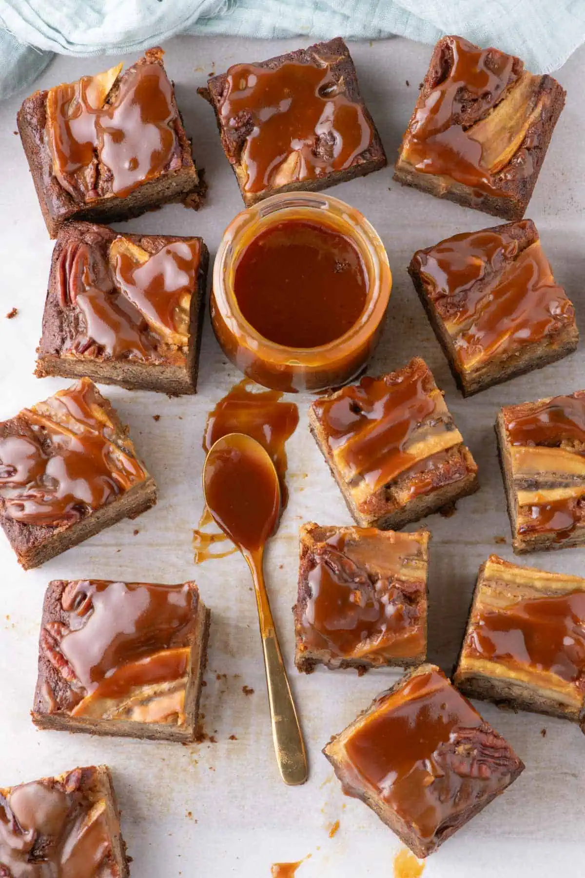  Overhead shot of dessert slices arranged on parchment with decorative banana slices on top and jar of caramel