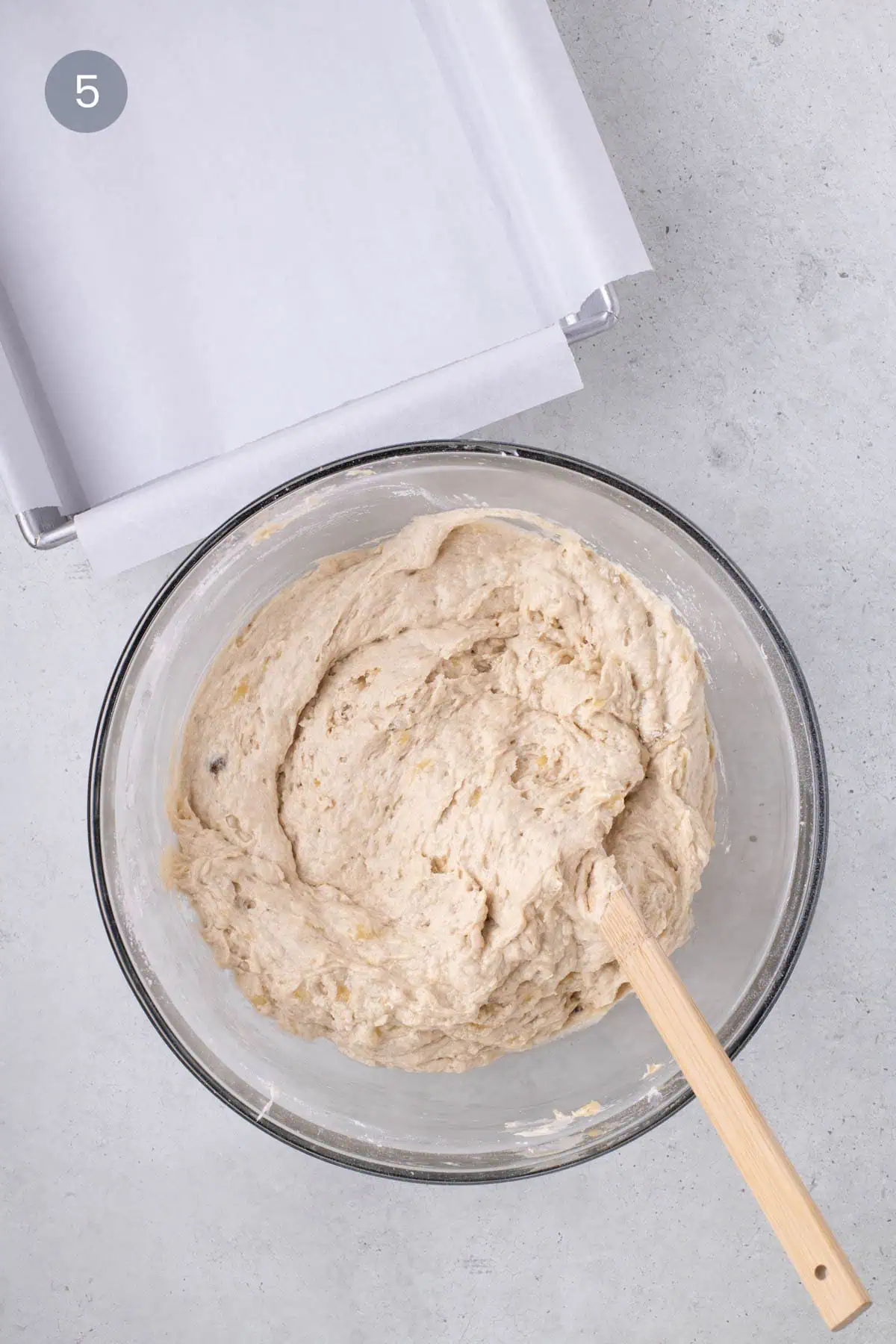 Banana bread batter spread in a parchment-lined square pan, ready for the oven.