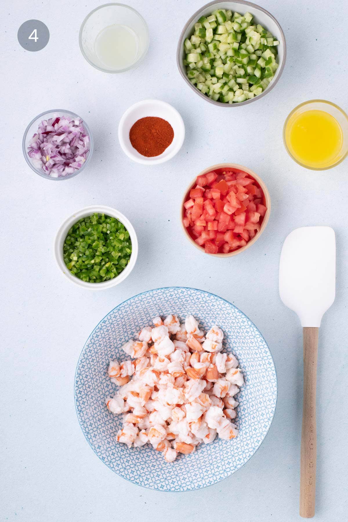 Chopped shrimp in a bowl with diced cucumber, tomato, red onion, jalapeño, lime juice, orange juice, and smoked paprika ready to make Mexican shrimp ceviche