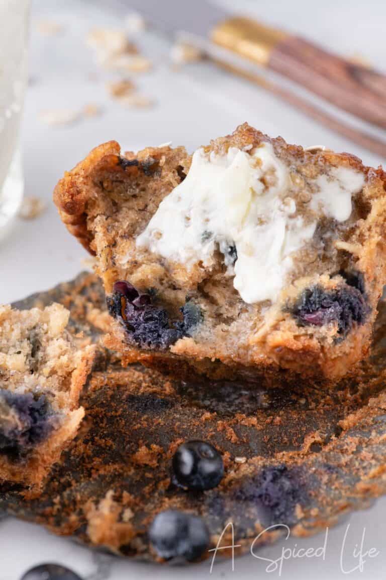 Inside of a muffin with butter melting into the warm center, highlighting the moist crumb and blueberry pockets.