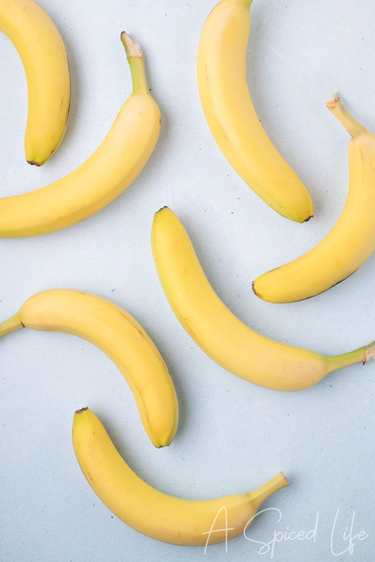 Multiple ripe bananas arranged on a light blue surface
