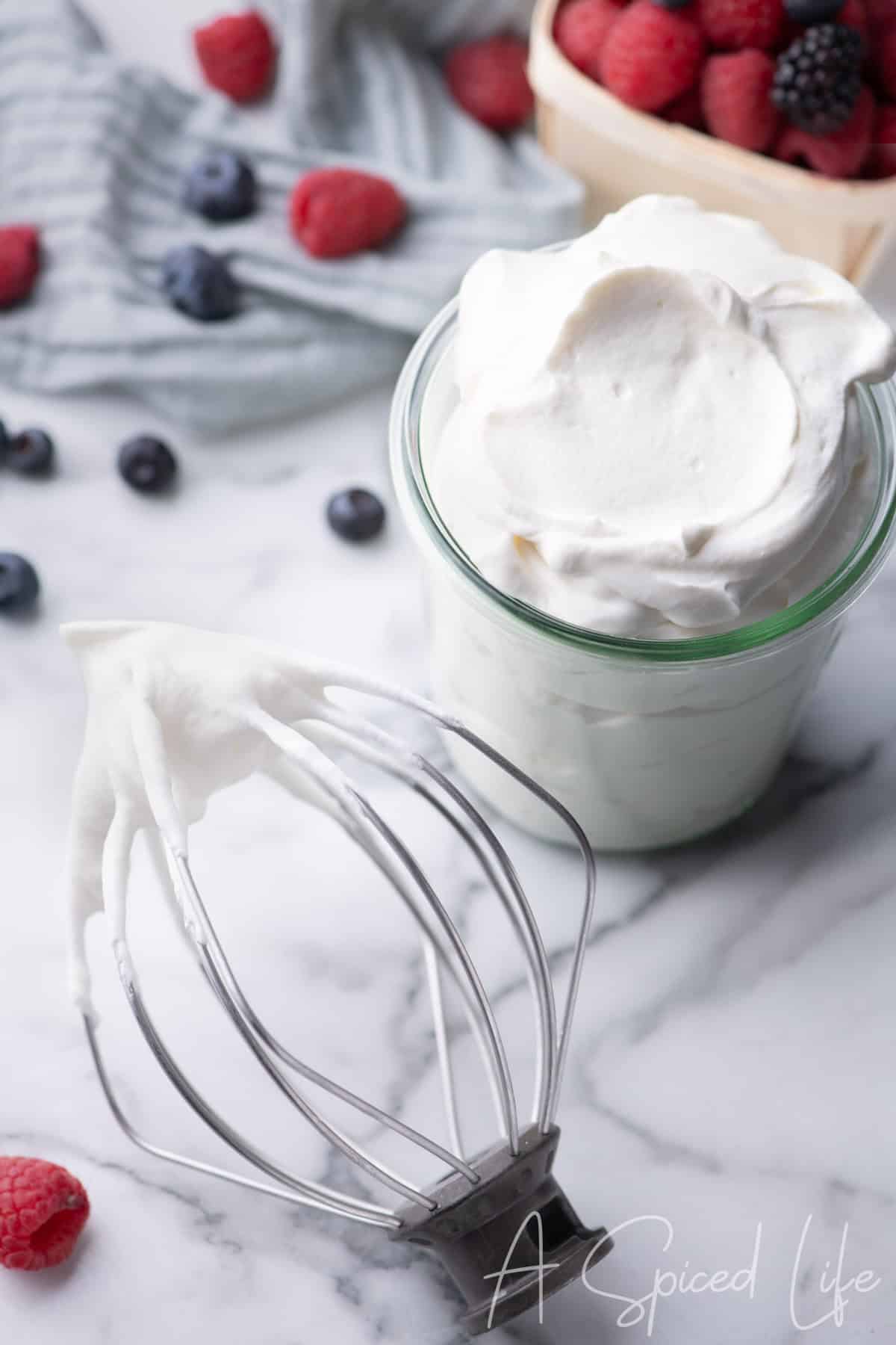Glass filled with homemade Chantilly cream topped with fresh raspberries