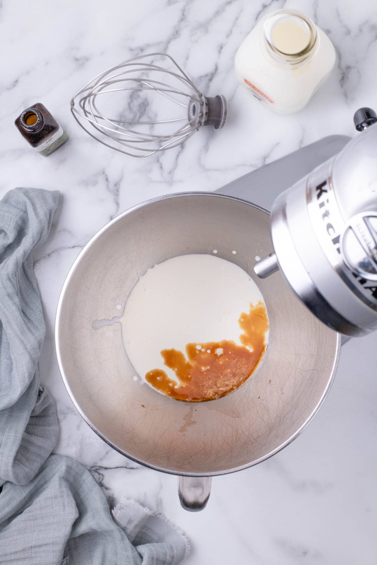 Heavy cream and vanilla extract in a stand mixer bowl before whipping.