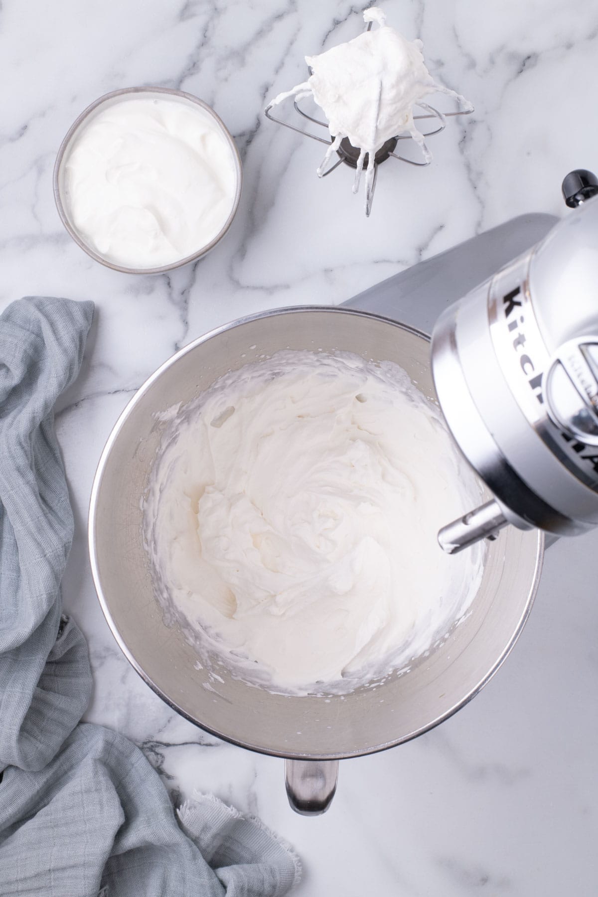 Whipped cream at soft peak stage on a whisk attachment.