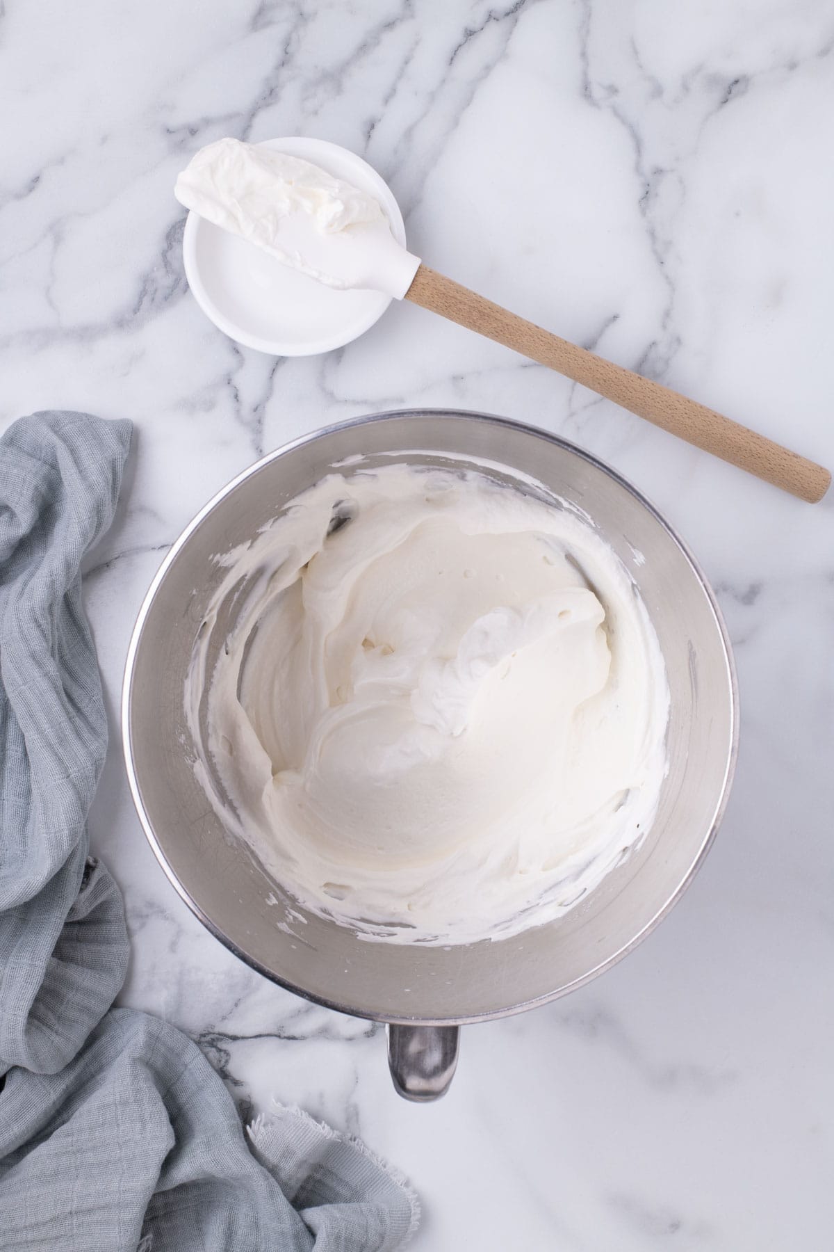 Finished Chantilly-style whipped cream in a mixing bowl with spatula.