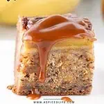 Straight-on photo of banana bread bar with salted caramel drizzle, banana in the background.