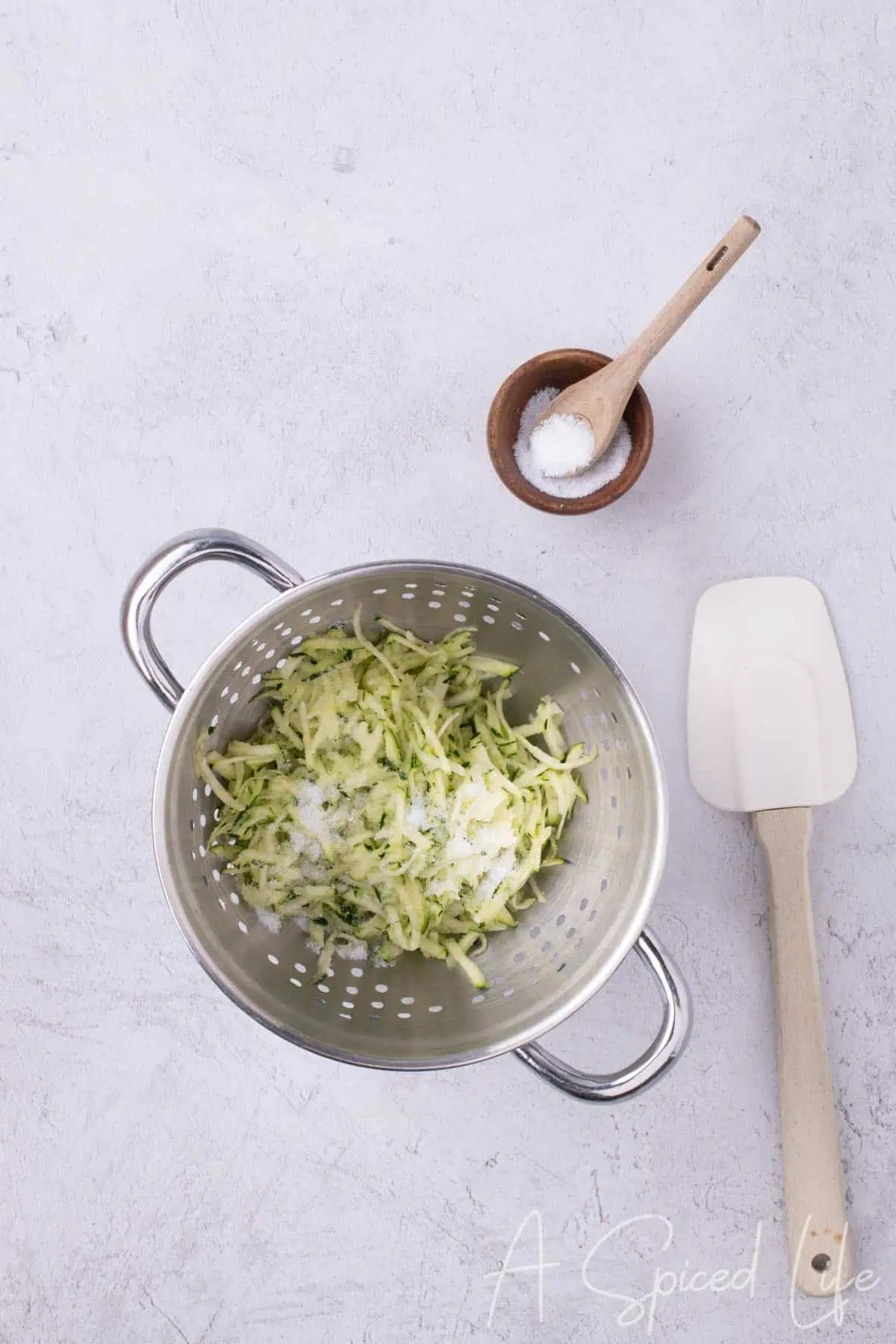 Zucchini in a colander with salt sprinkled on top to draw out moisture.