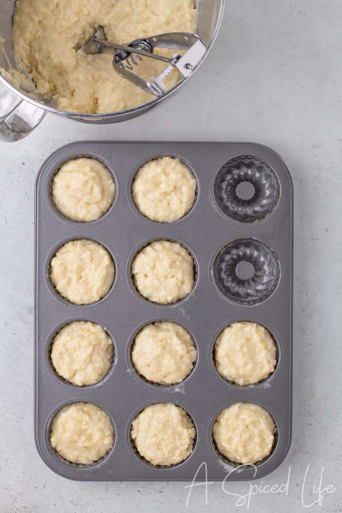 Cookie scoop filling mini bundt cake pan cavities three-quarters full with batter