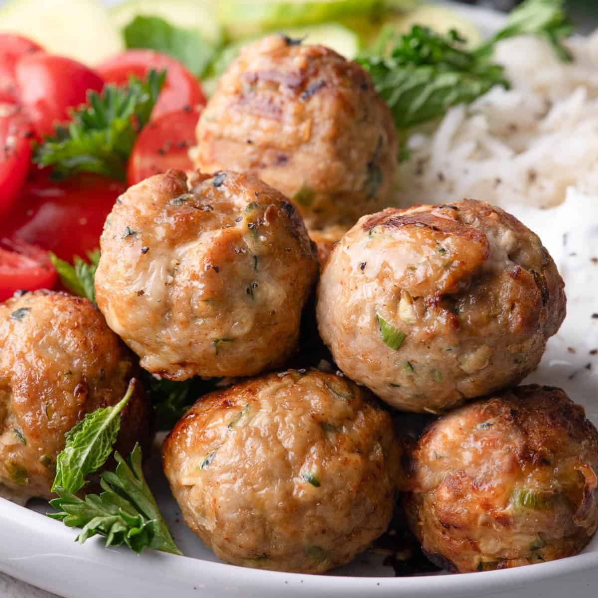 Air Fryer turkey meatballs served with rice, cherry tomatoes, and fresh herbs.