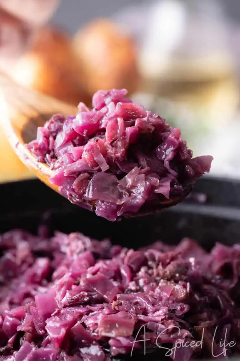 Spoonful of braised red cabbage over pot with blurred holiday background