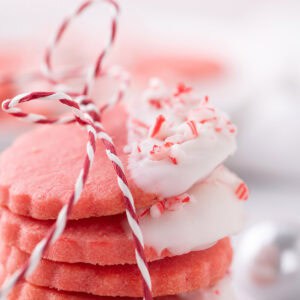 Stack of pink peppermint cookies dipped in white chocolate and topped with crushed candy canes