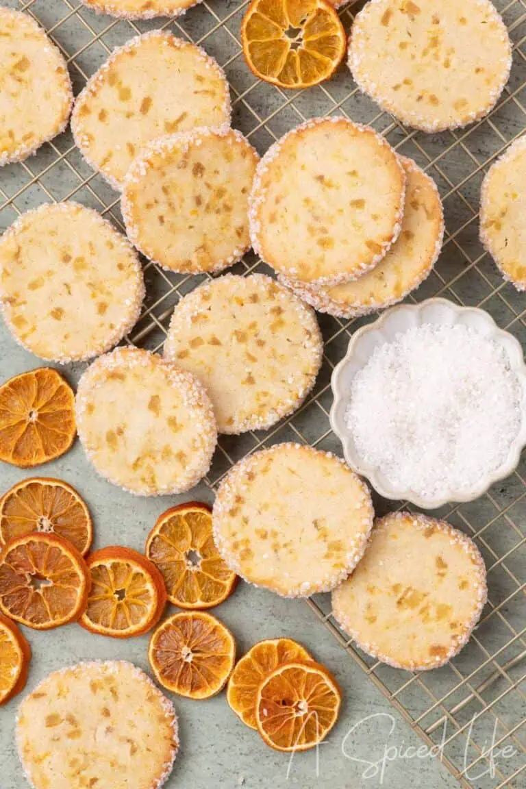 Orange ginger slice cookies cooling on a wire rack with dried orange slices and sanding sugar