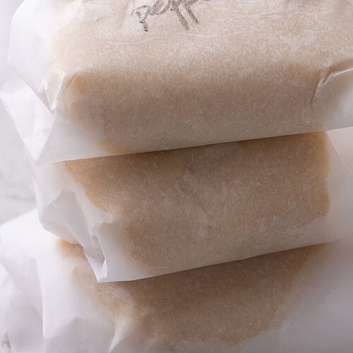 Close-up of wrapped cookie dough labeled peppermint, stacked and ready for chilling.