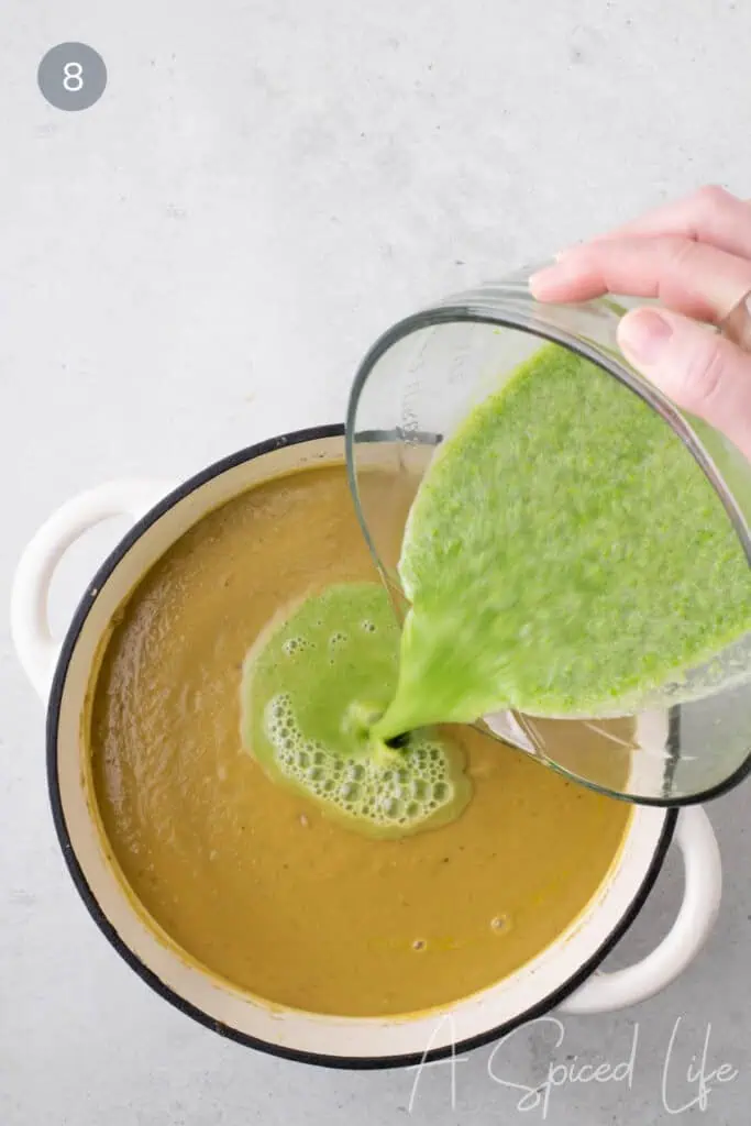 Bright green pea purée being poured into blended split pea soup in a pot.