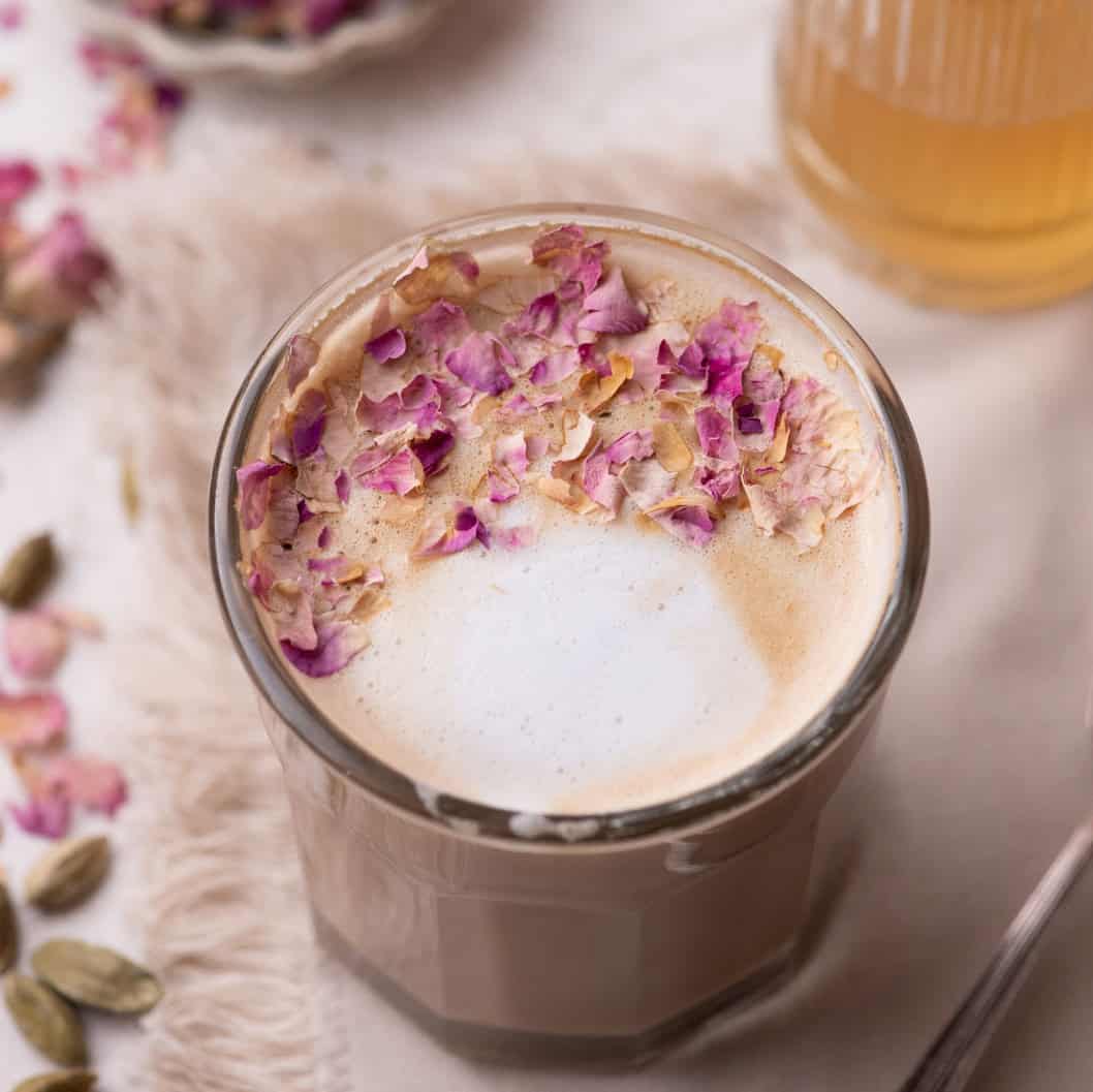 Rose Cardamom Latte topped with crushed rose petals and creamy milk foam.