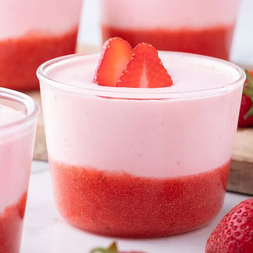 Strawberry mousse in a glass dessert cup topped with fresh strawberries