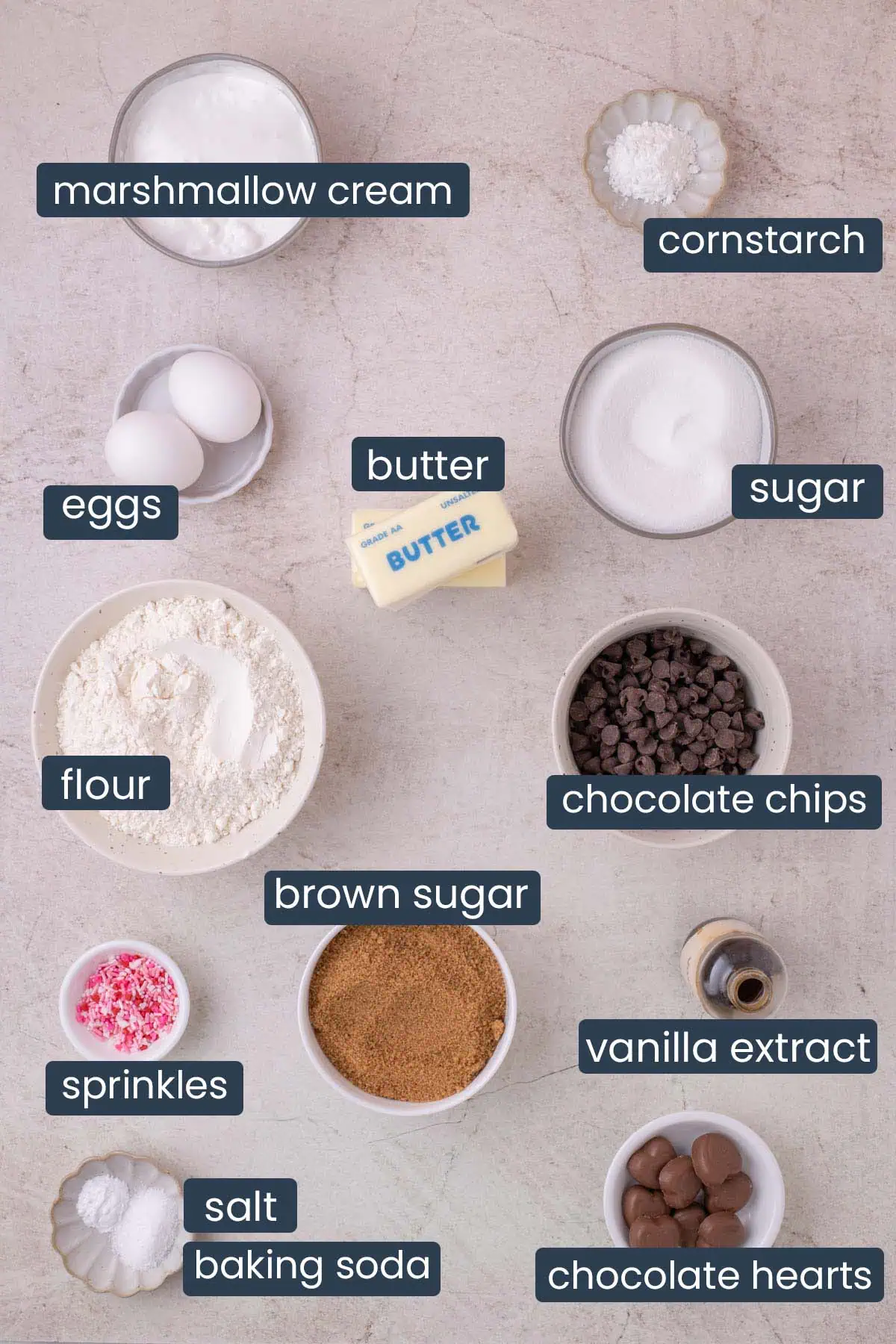 Ingredients for heart-shaped chocolate chip cookie including marshmallow fluff, chocolate chips, brown sugar, butter, eggs, and chocolate hearts