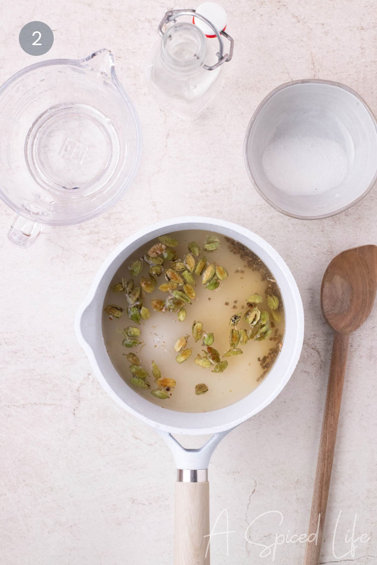 Cardamom pods simmering with sugar and water in a small saucepan
