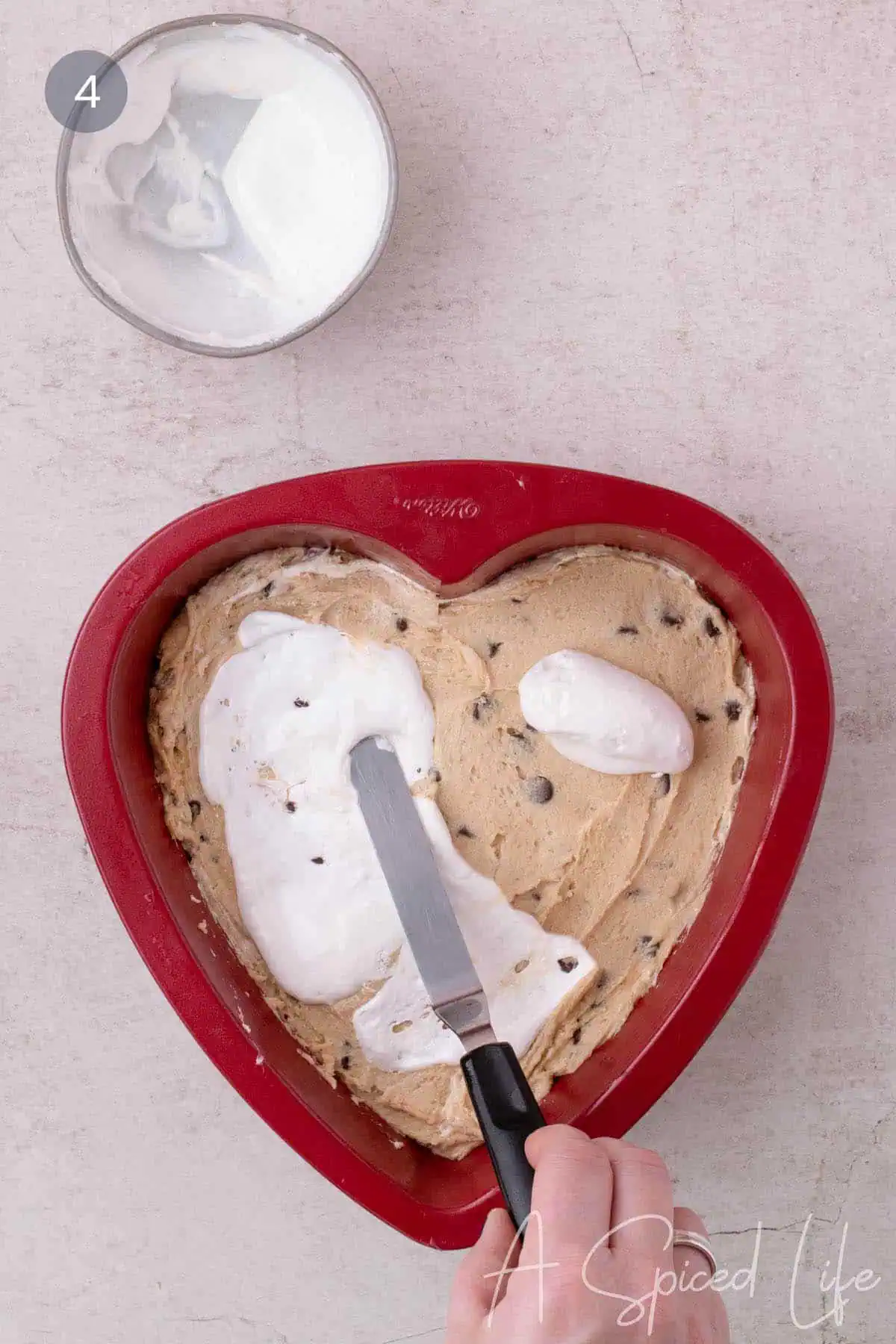 Marshmallow cream spread over cookie dough in heart pan