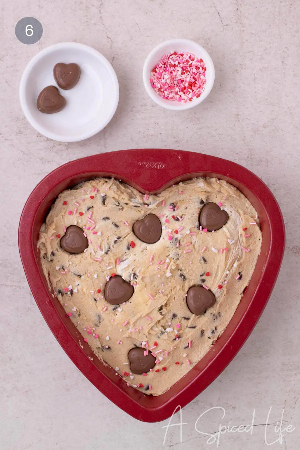 Unbaked heart shaped cake topped with chocolate hearts and sprinkles