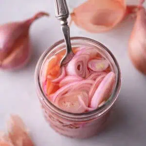 Jar of quick pickled shallots with pink brine and sliced shallots