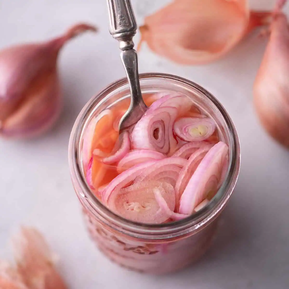 Jar of quick pickled shallots with pink brine and sliced shallots