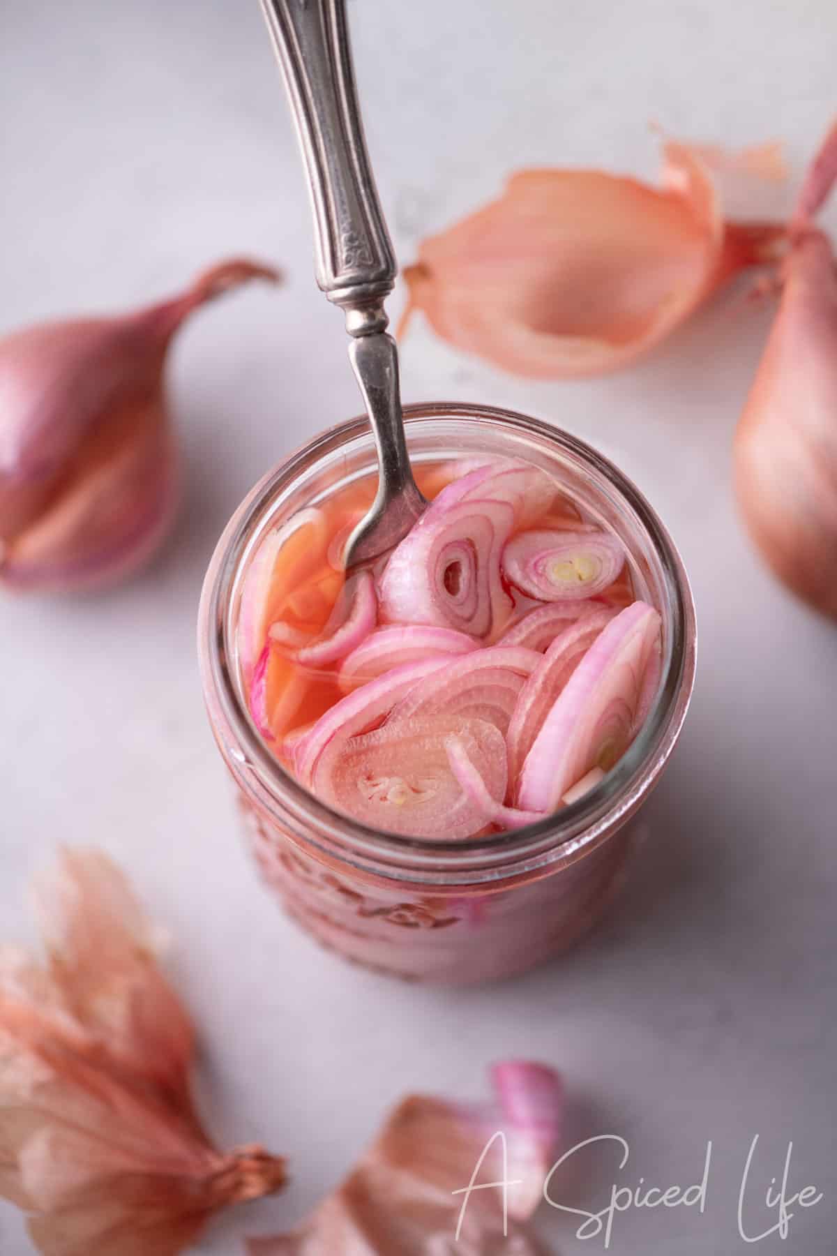 Jar of quick pickled shallots with pink brine and sliced shallots