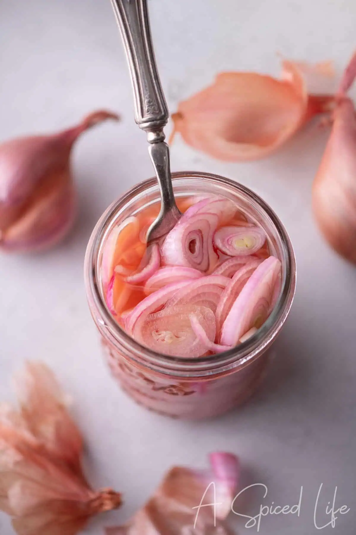 Jar of quick pickled shallots with pink brine and sliced shallots