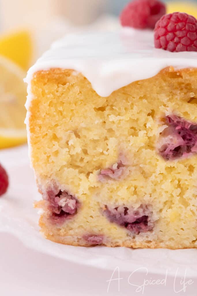 Moist raspberry lemon loaf cake slice with glaze and fresh raspberries