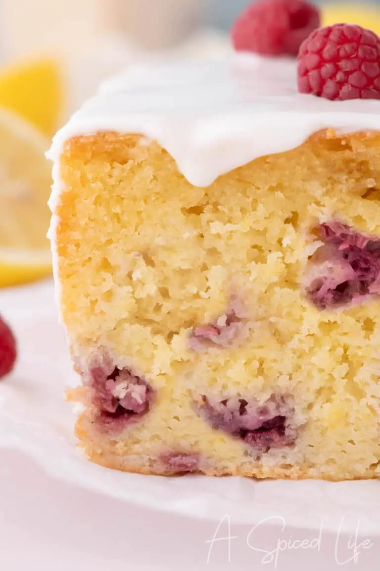 Moist raspberry lemon loaf cake slice with glaze and fresh raspberries
