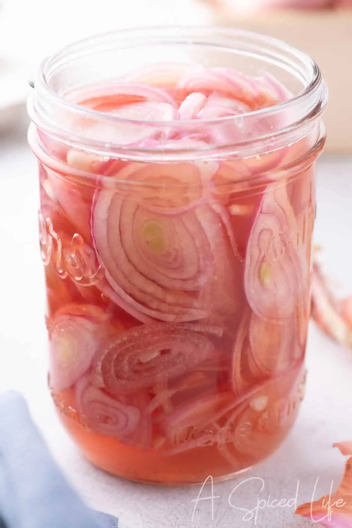 Close-up of jar filled with thinly sliced pickled shallots in pink vinegar brine