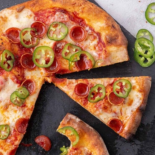 Slices of Diavola pizza topped with pepperoni, jalapeños, and mozzarella.
