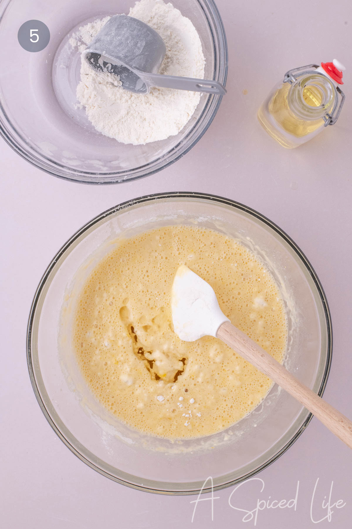 Vegetable oil being added to lemon loaf batter in a glass bowl