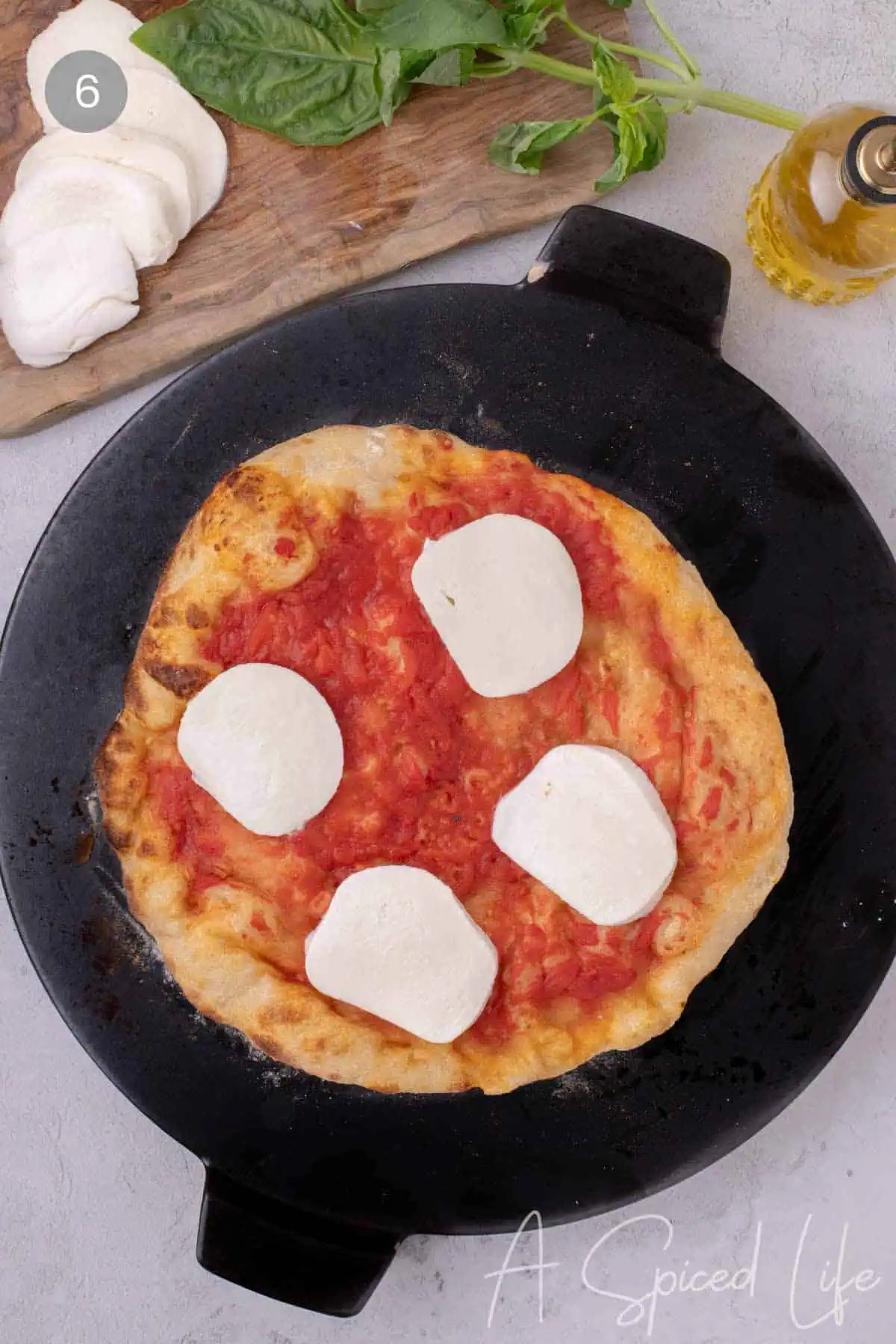 Neapolitan-style pizza with tomato sauce and mozzarella cooking on pizza steel