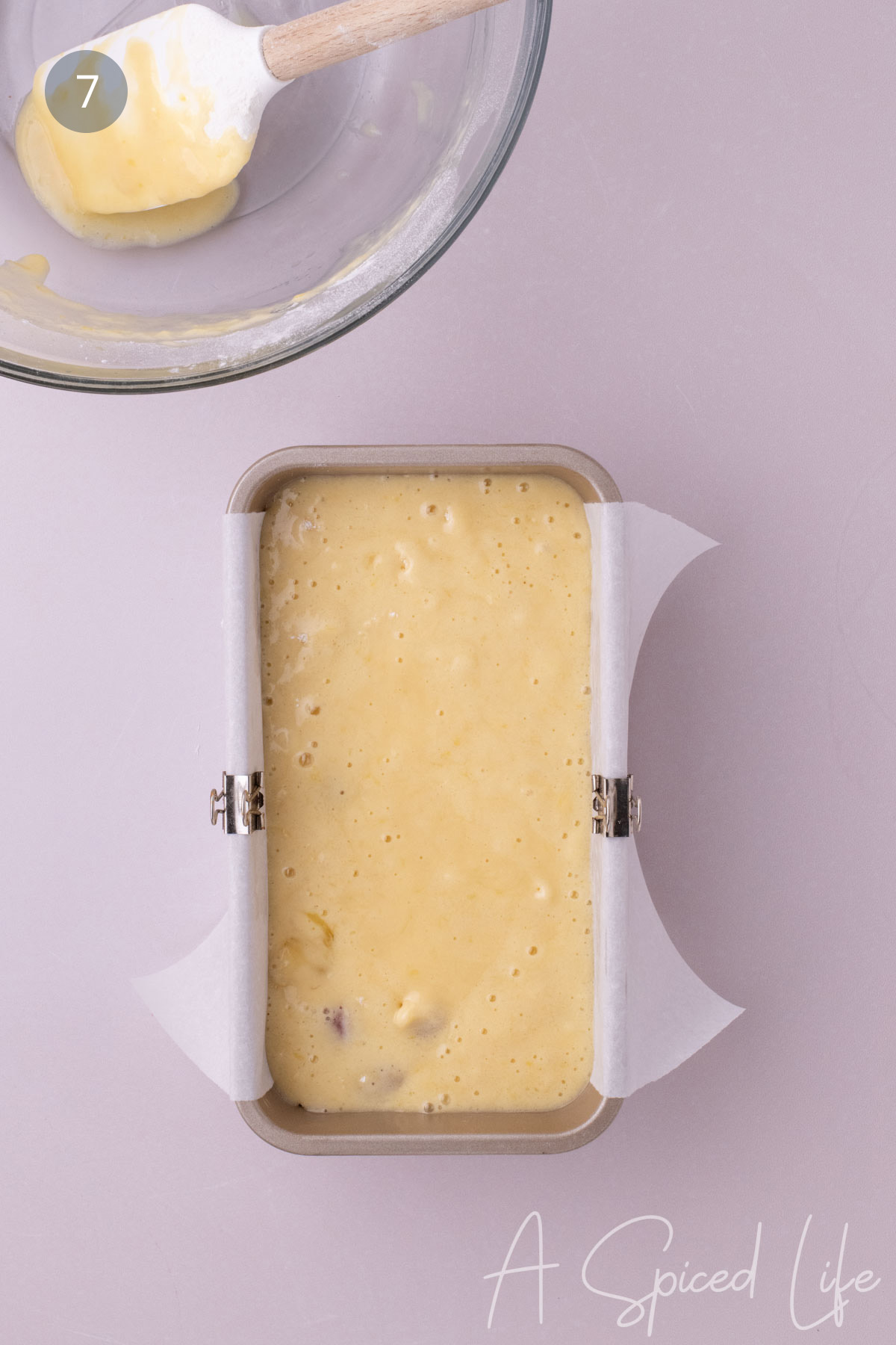Raspberry lemon loaf batter poured into a parchment-lined loaf pan