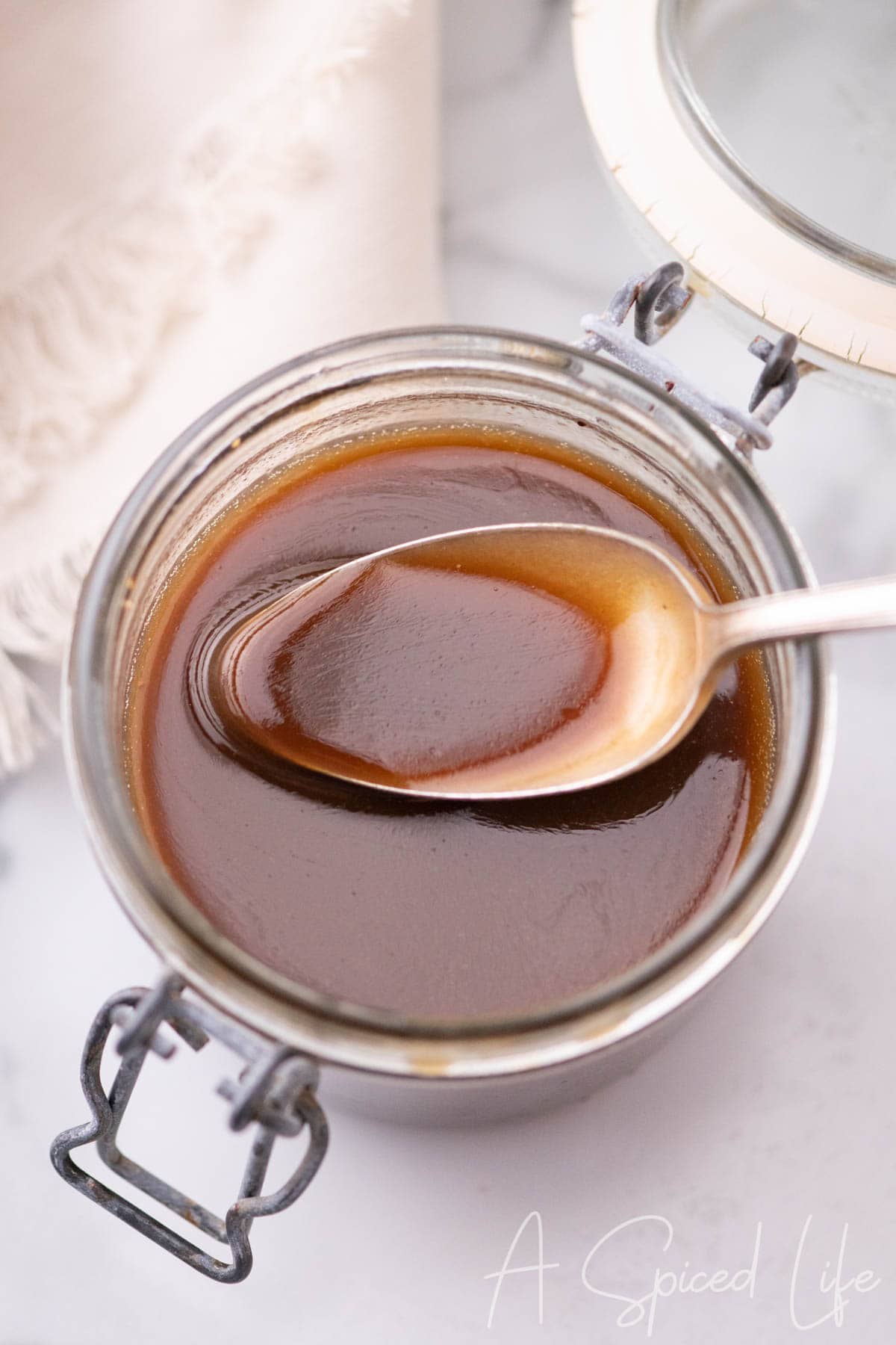 Spoon lifting smooth lemon balsamic dressing from a glass jar.