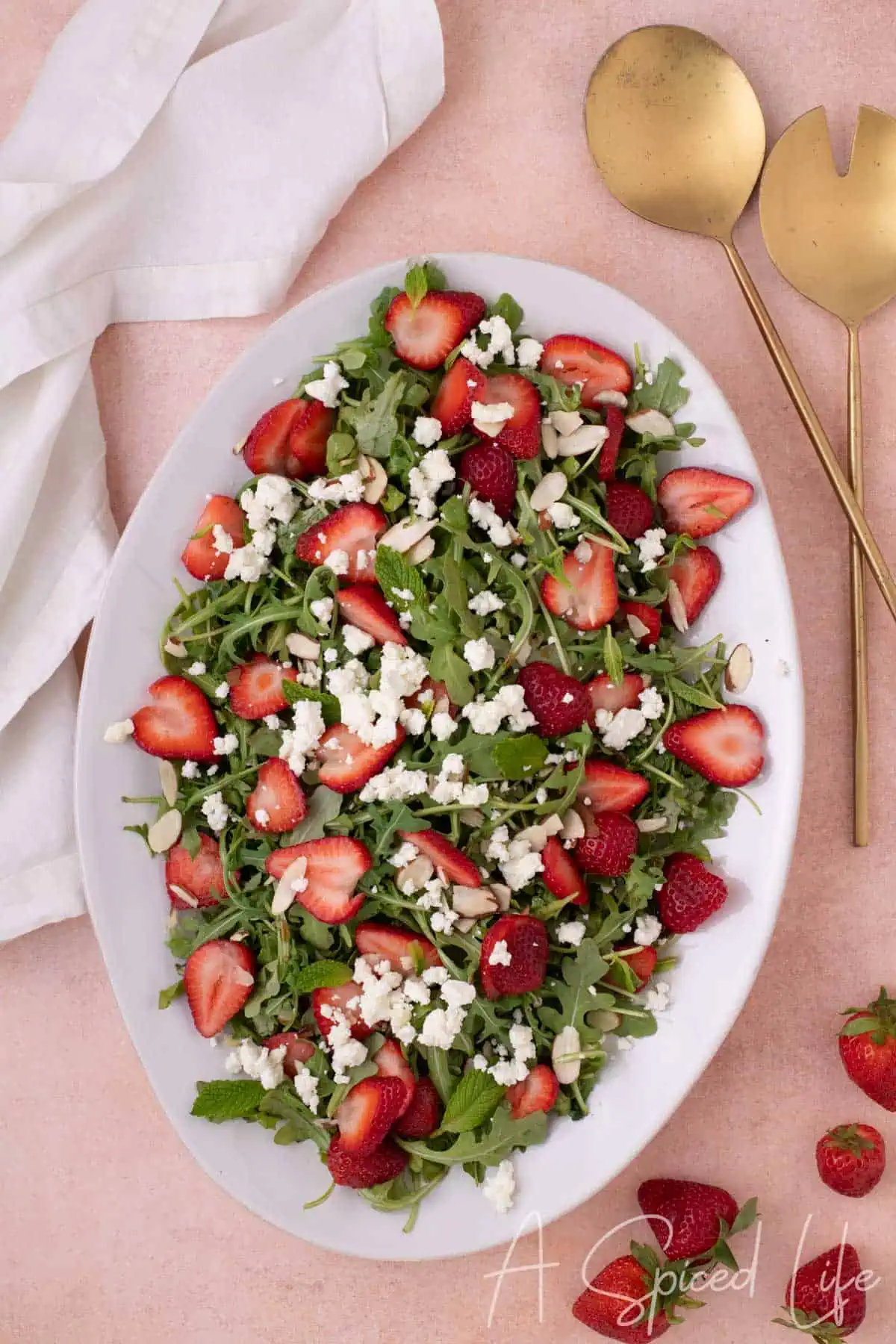 Close-up of arugula salad with sliced strawberries and crumbled goat cheese on a serving platter