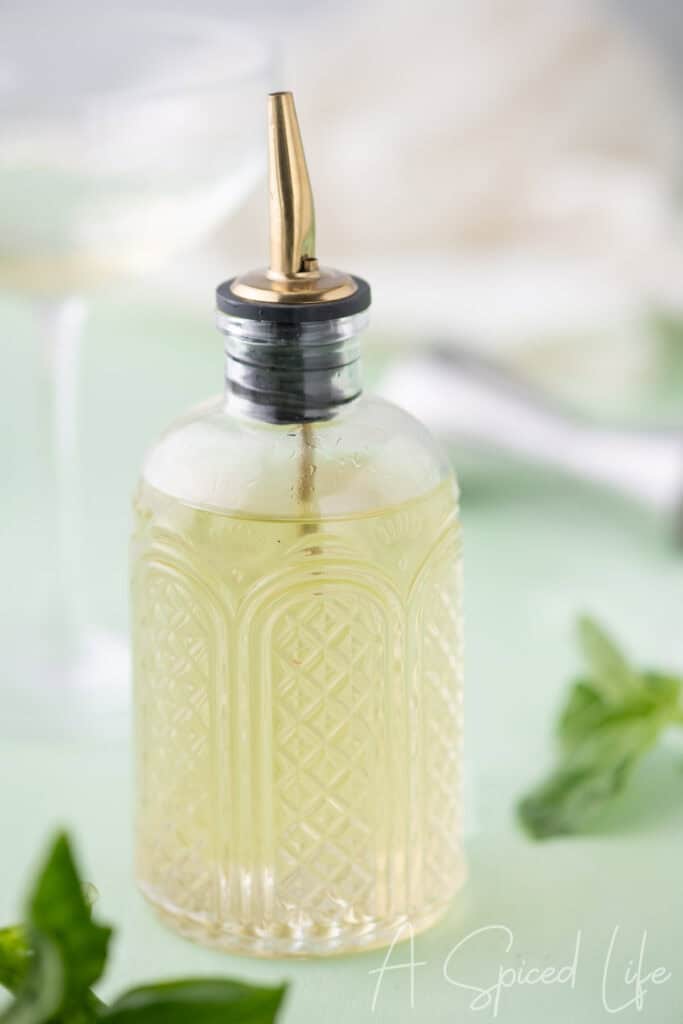 Close-up of homemade basil syrup in a glass bottle with a pour spout
