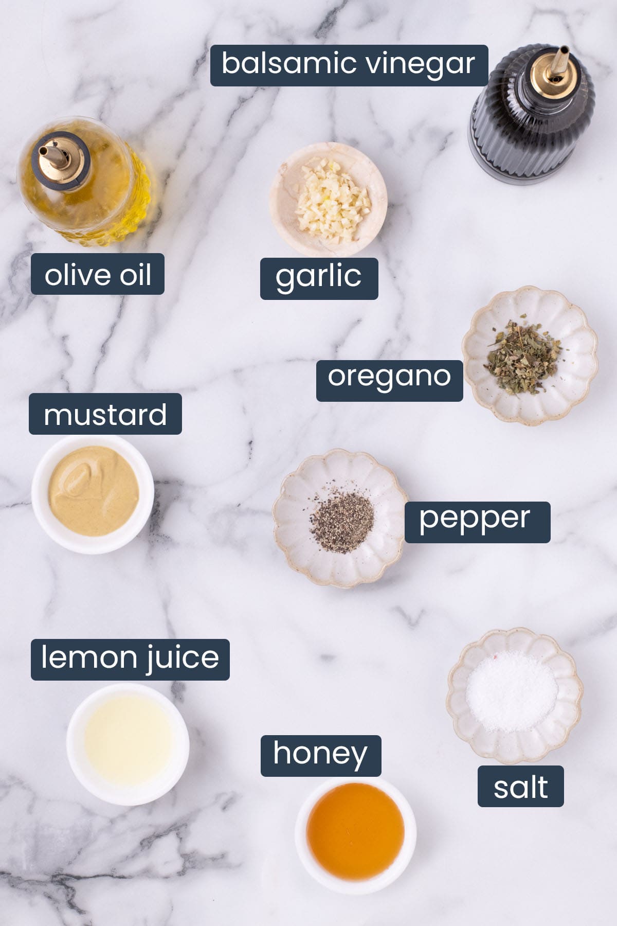 Ingredients for lemon balsamic dressing including balsamic vinegar, olive oil, garlic, mustard, lemon juice, honey, salt, pepper, and oregano.