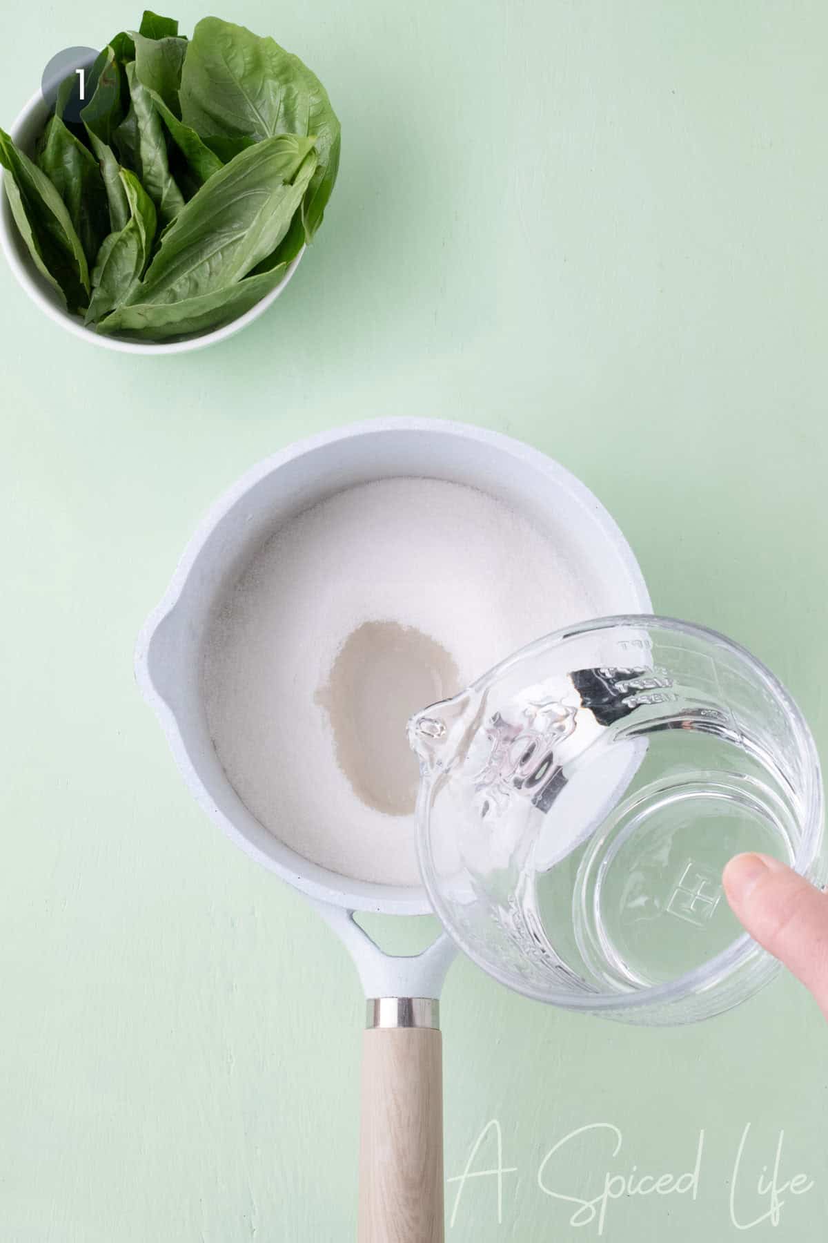 Sugar and water being combined in a saucepan to make basil simple syrup