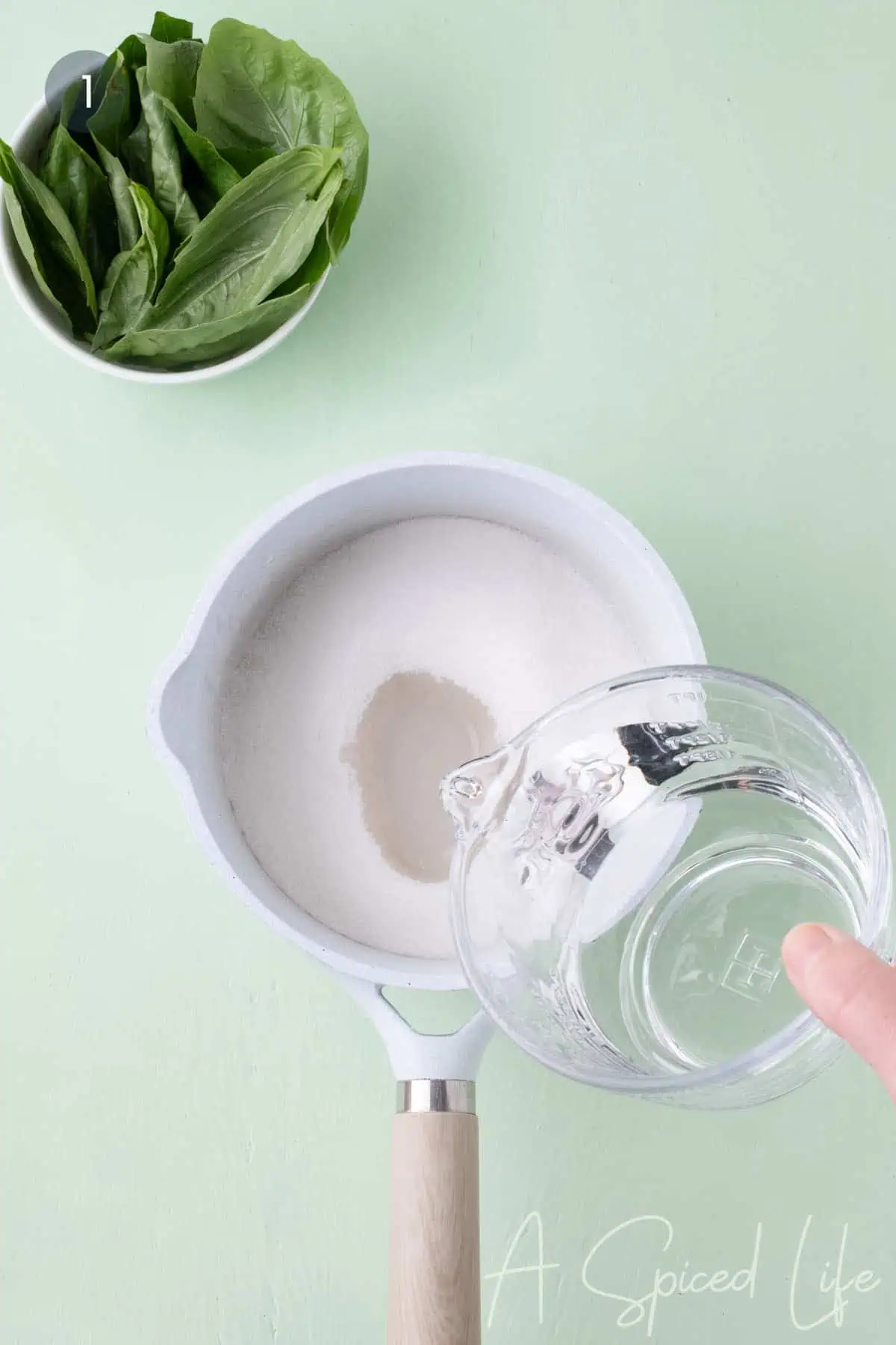 Sugar and water being combined in a saucepan to make basil simple syrup