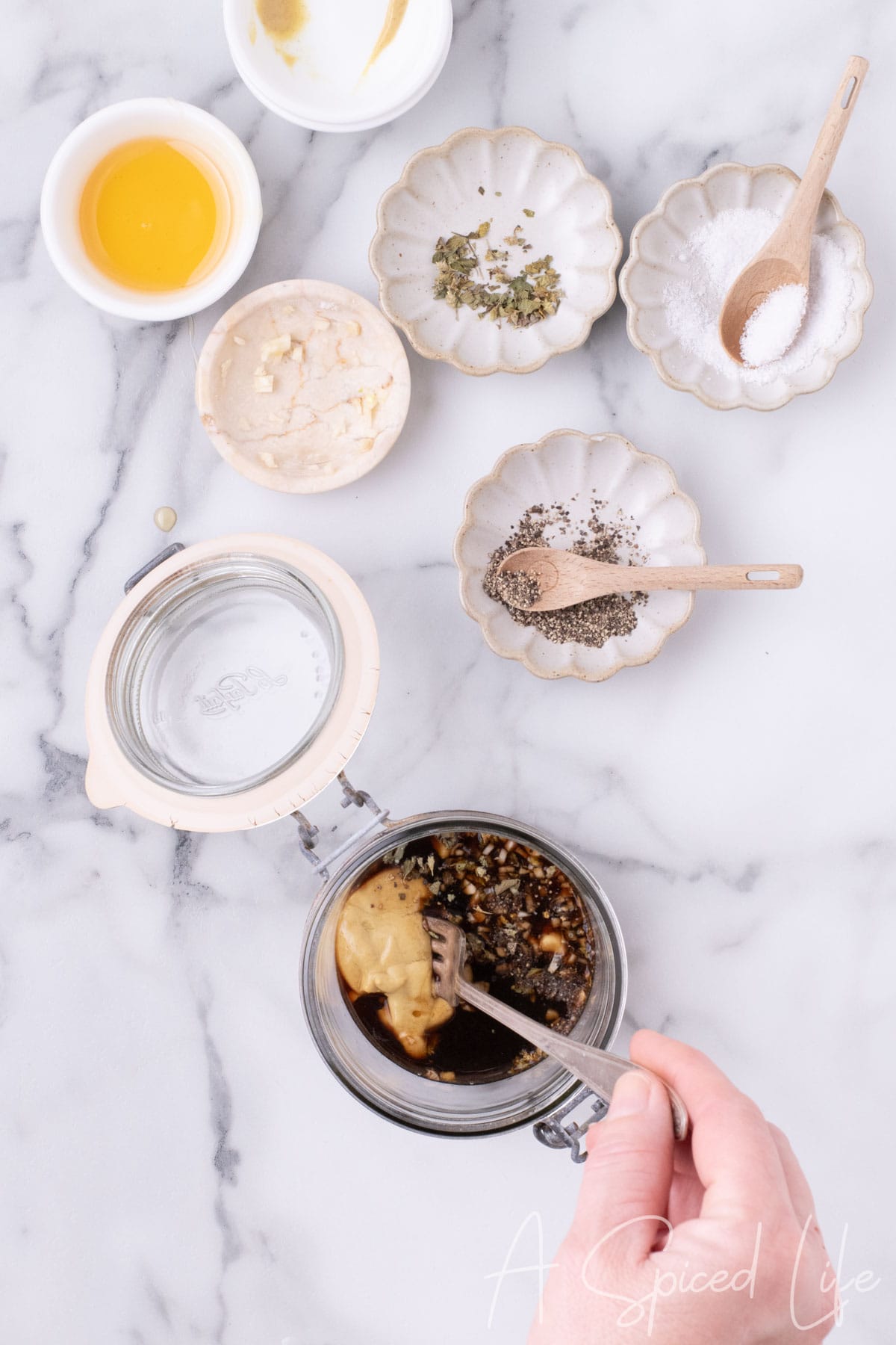Mixing balsamic vinegar, honey, lemon juice, mustard, garlic, and spices in a jar.