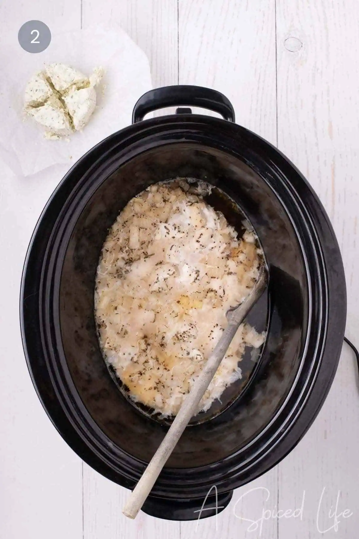 Boursin cheese added to cooked chicken and broth in a slow cooker.