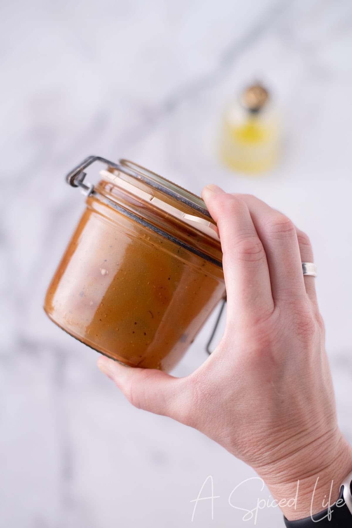 Hand shaking a sealed jar to emulsify balsamic dressing until smooth.