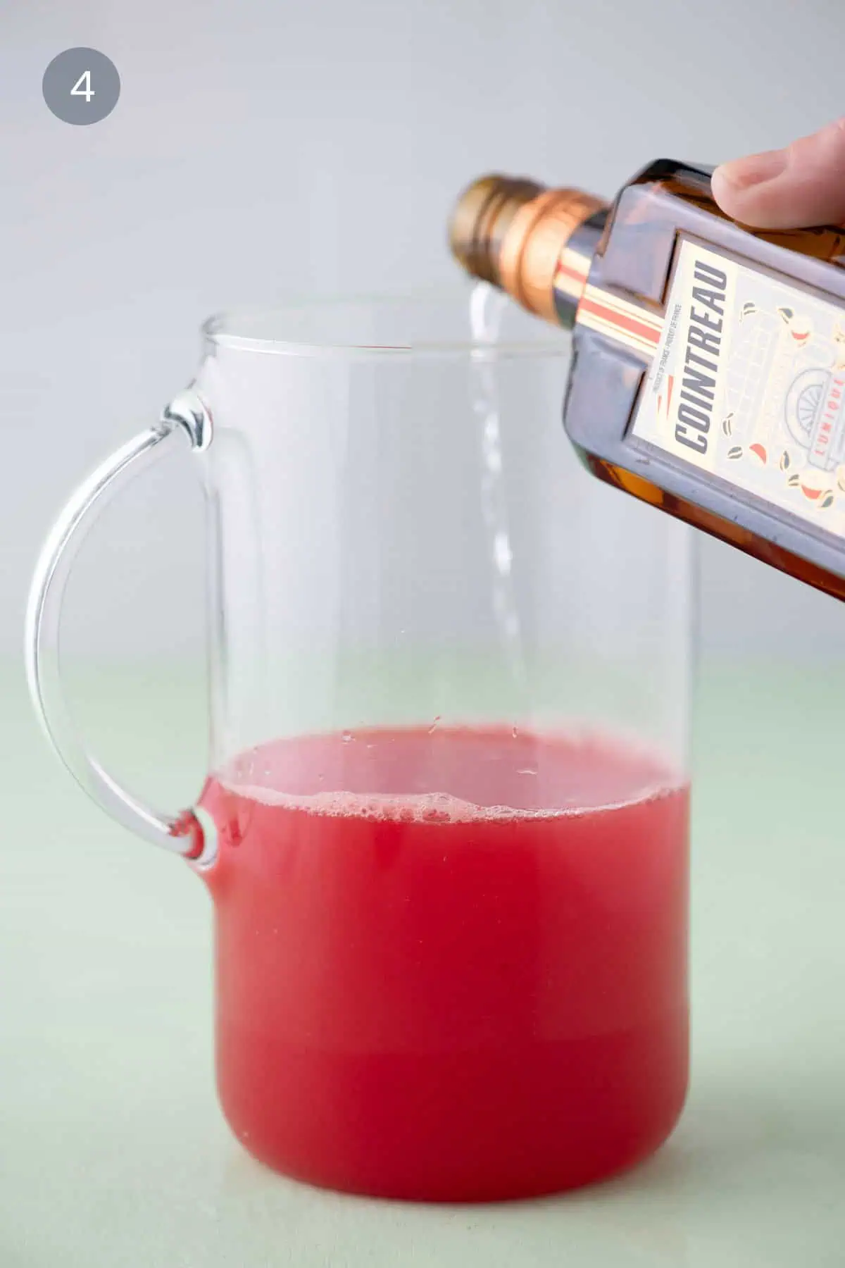 Adding orange liqueur to watermelon margarita mixture