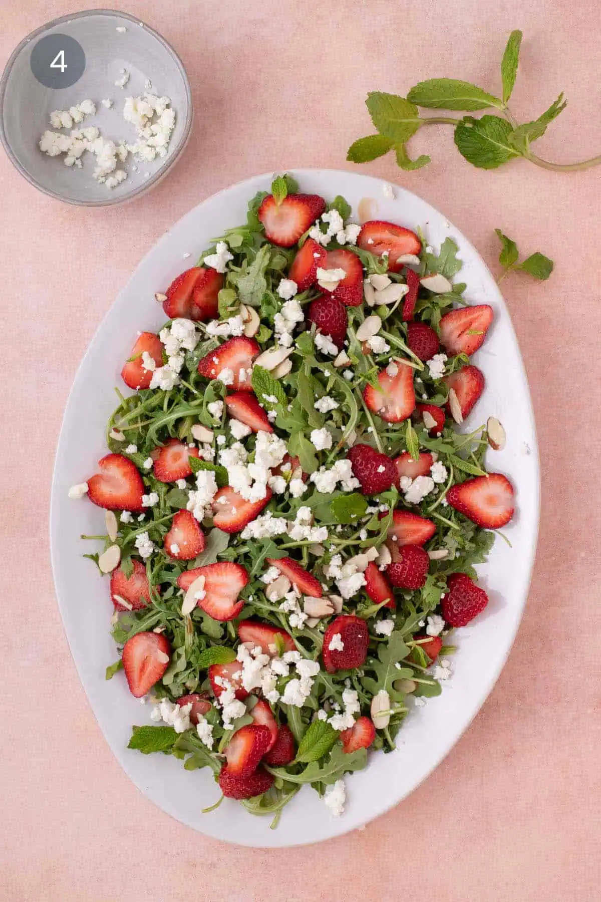 Finished salad topped with crumbled goat cheese and fresh mint leaves