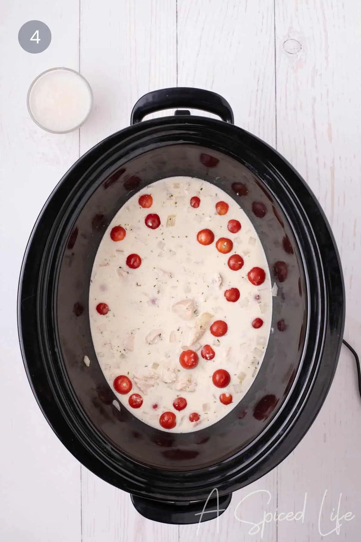 Cherry tomatoes added to creamy chicken sauce in a slow cooker.