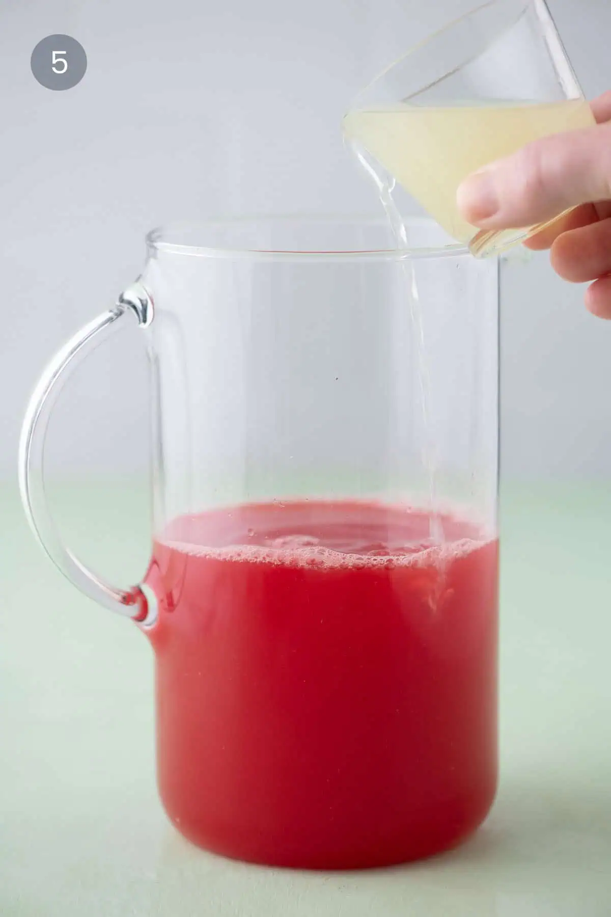 Pouring fresh lime juice into watermelon margarita mixture