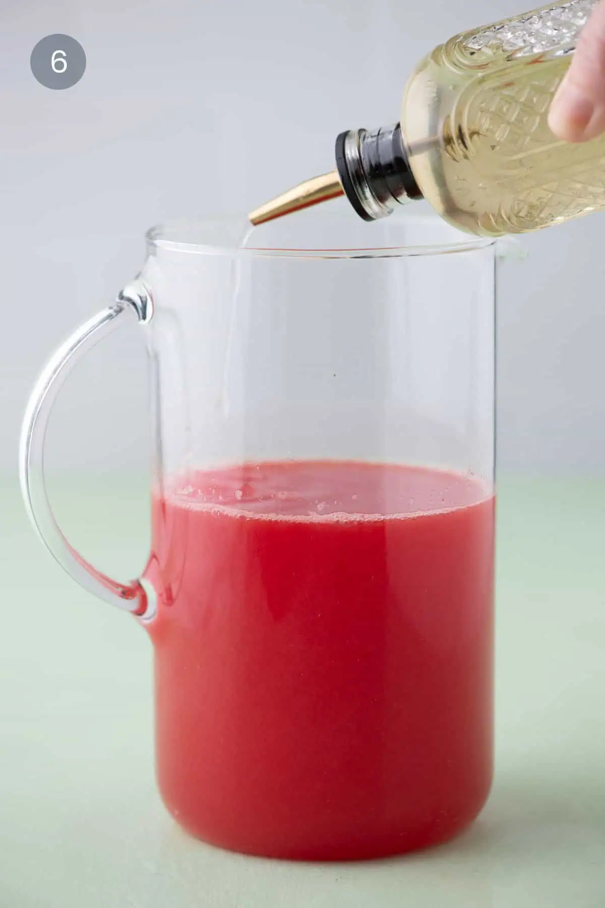 Pouring basil simple syrup into watermelon margarita pitcher