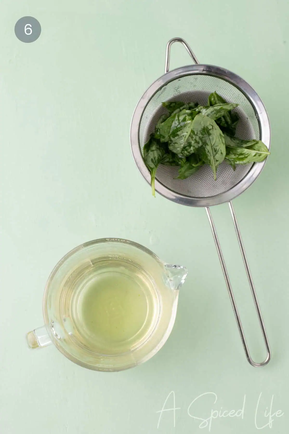 Strained basil simple syrup in a glass measuring cup with basil leaves removed